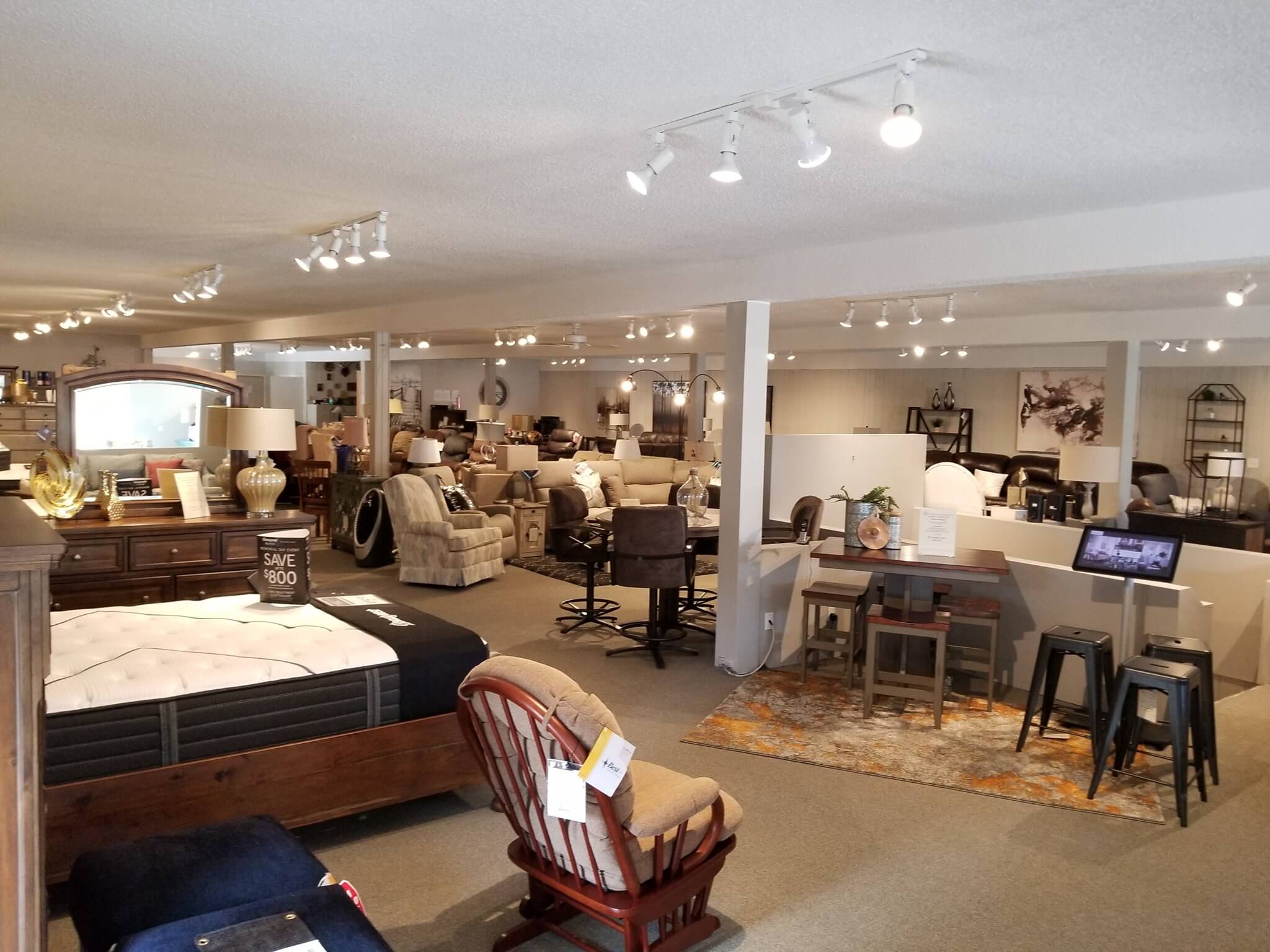 Contemporary furniture showroom featuring a coordinated dining table, comfortable chairs, and warm natural finishes